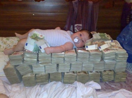 грудной ребенок лежит на пачках денег