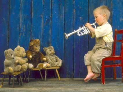 мальчик играе на трубе для своих игрушечных медведей