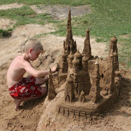 мальчик строит замок из песка