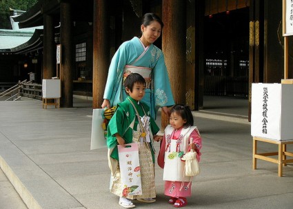 Японская женщина со своими детьми идут на праздник