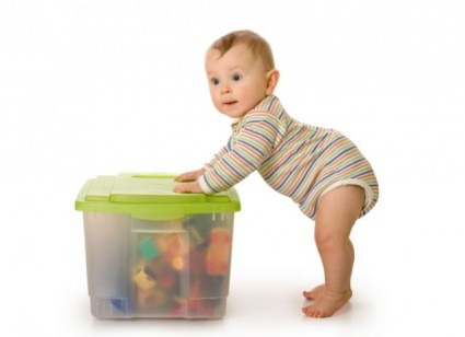 малыш стоит возле коробки с игрушками