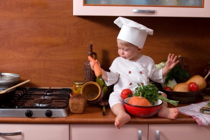 Малыш в костюме повара на кухне