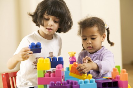 Светлокожая и темнокожая девочки играют с конструктором