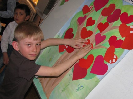 Мальчик украшает сердечками плакат