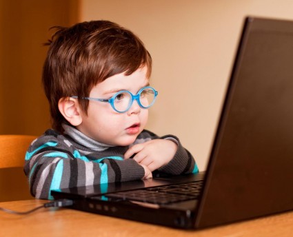 Малыш к очках перед ноутбуком