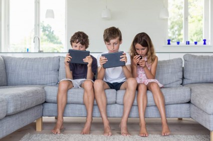Дети на диване с планшетами и смартфоном