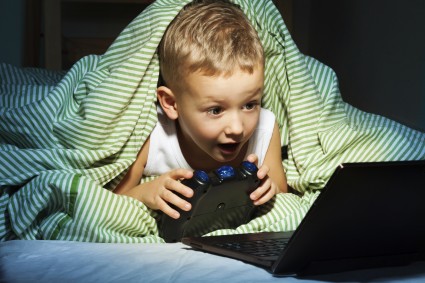 Малыш под одеялом играет в компьютерную игру