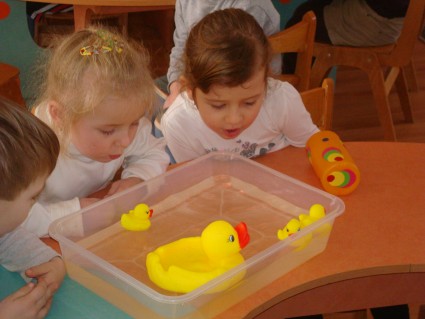Дети дуют на игрушки в воде