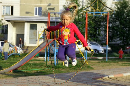 Девочка прыгает через скакалку во дворе