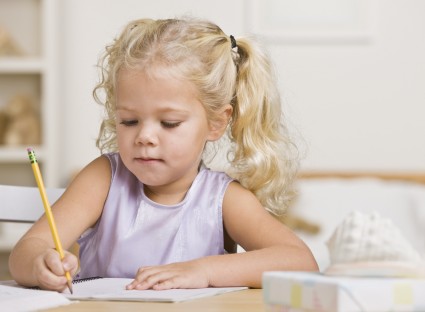 Девочка пишет карандашом в тетради