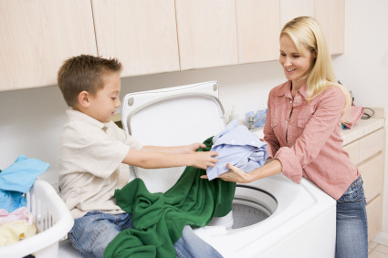 Мальчик и женщина закладывают вещи в стиральную машину