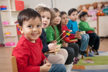 Дети сидят с барабанными палочками (на переднем плане мальчик в красной рубашке)