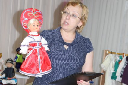 Воспитательница держит куклу в национальном костюме