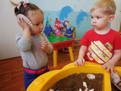 Мальчик и девочка у жёлтой формы с песком