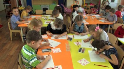 Дети в группах сидят за столами и рисуют красками
