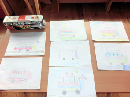 Работы на тему «Автобус, украшенный флажками» разложены на столе