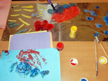 На столе лежит фольга, на которой нарисован автобус; рядом бумага и краски