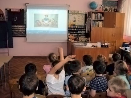 Дошкольники смотрят на мультимедийный экран с изображением дымковских игрушек