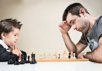 Мальчик играет в шахматы с отцом