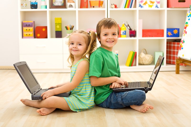 девочка и мальчик держат на коленях ноутбуки