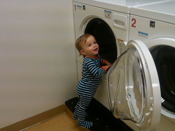 маленький мальчик стоит возле стиральной машины