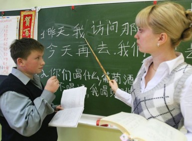 Учитель показывает на доске иероглифы ученику
